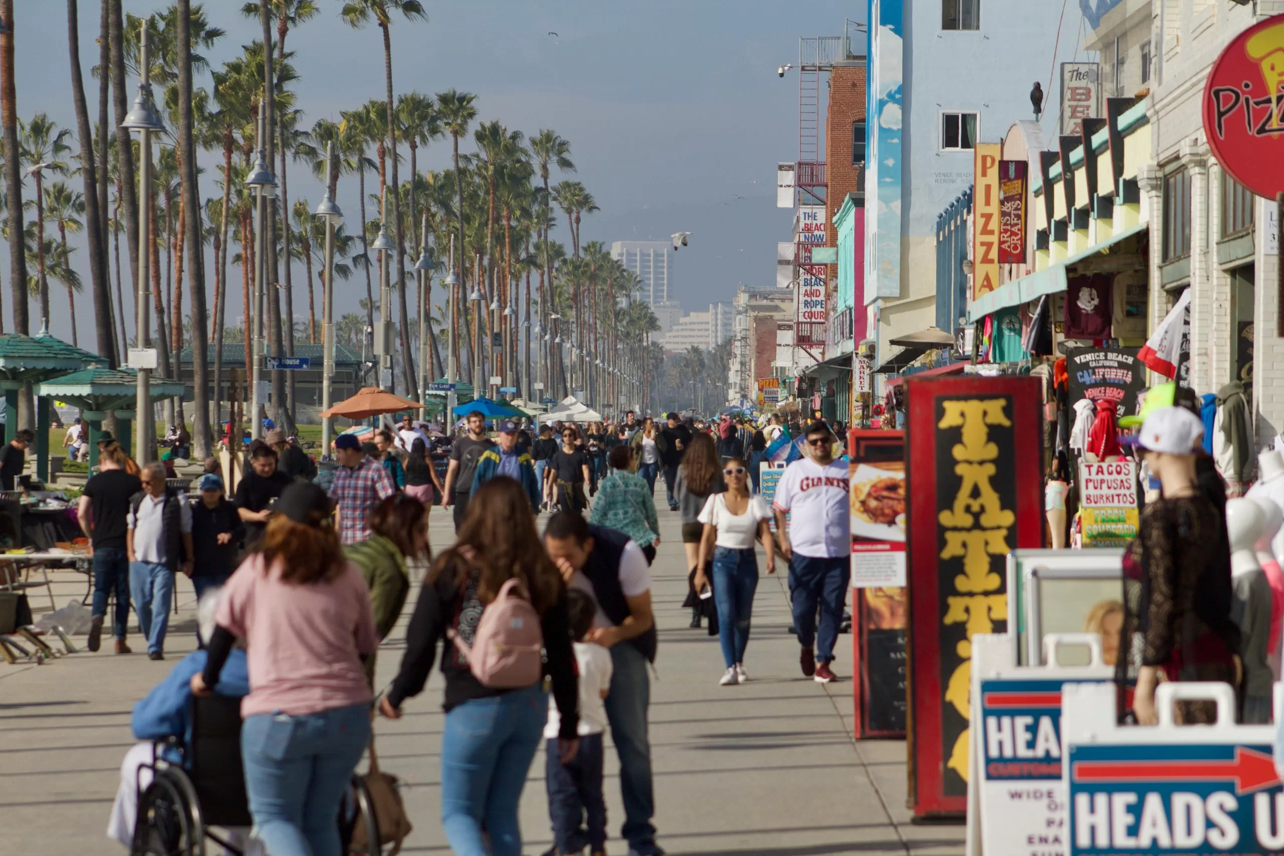 Crowds enjoying a sunny day on the Venice Beach boardwalk, a vibrant stop on a Los Angeles family vacation